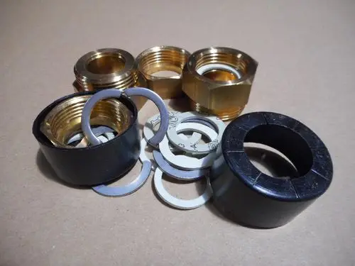 Auf dem Bild sind verschiedene Verbindungsstücke aus Metall und Kunststoff zu sehen, die typischerweise für Rohrinstallationen verwendet werden. Remeha Produkte sind ebenfalls enthalten.